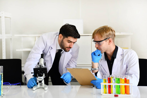 Δύο επιστήμονες έχουν κάνει ένα ικανοποιητικό πείραμα με τα χημικά δείγματα στο εργαστήριο.. - Φωτογραφία, εικόνα