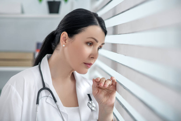 Successful woman in white medical coat near the window. - Фото, зображення