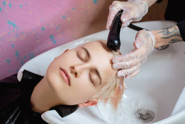 La peluquera lava la cabeza de una mujer a un cliente. Colorear
. - Foto, Imagen
