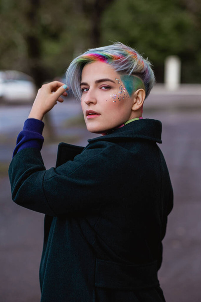 Portrait of a young beautiful woman with a short haircut and dyed hair. Grey main color and yellow, green, blue and red hair color. - Фото, изображение