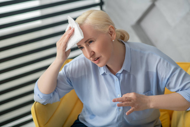 Adult woman with a napkin near her forehead - Φωτογραφία, εικόνα
