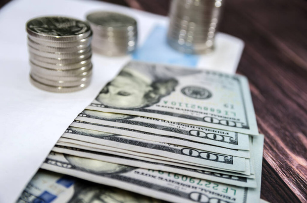 Stapel von Münzen und Dollars in einem Umschlag auf einem hölzernen Hintergrund. Sparkonzept oder Sparkonzept - Foto, Bild