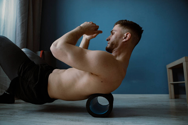 guy massaging back with roller at home - Photo, image