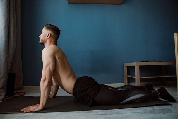 bebaarde spier man doen terug stretching thuis - Foto, afbeelding