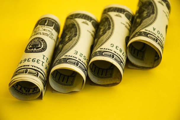 Dólares americanos en rollos. Ahorro de concepto de dinero en el fondo amarillo con espacio de copia para el texto, Fondo del dólar. Dinero americano. La cuenta americana, Ahorros y Riqueza
 - Foto, Imagen