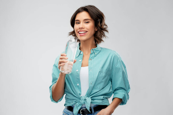 smiling woman drinking water from glass bottle - Foto, Bild
