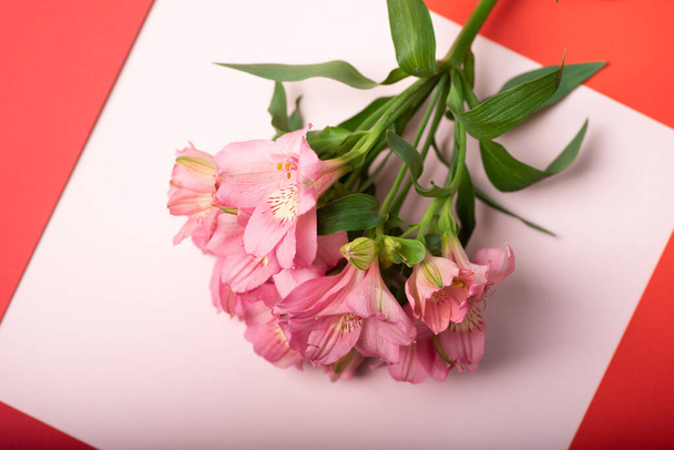 薄紫色のテーブルと赤いフレームの上にピンクの花の美しい花束。女性の日、母の日、春の花のための創造的なポストカード。トップ表示画像 - 写真・画像