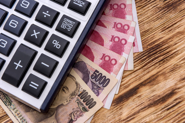 Kalkulator z chińskimi i japońskimi banknotami na drewnianym tle zbliżenie - Zdjęcie, obraz