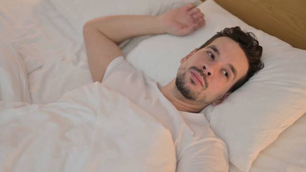 Unavený mladý muž se snaží spát v posteli - Fotografie, Obrázek