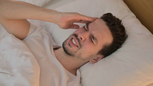 Портрет молодого человека с головной болью в постели
 - Фото, изображение