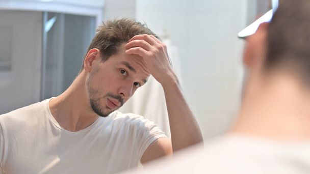 Jeune homme Fixation des cheveux dans le miroir
 - Photo, image