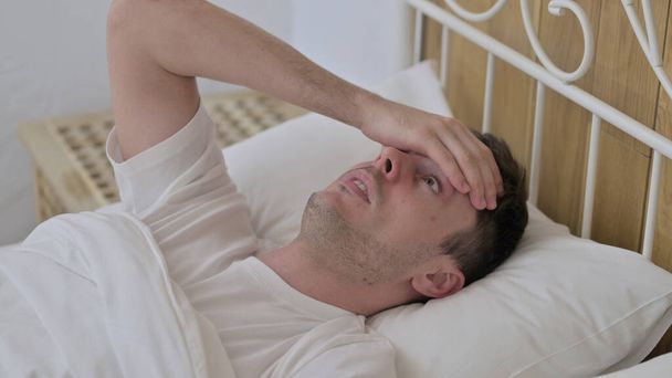 Bang jonge man wakker worden uit nachtmerrie in bed - Foto, afbeelding
