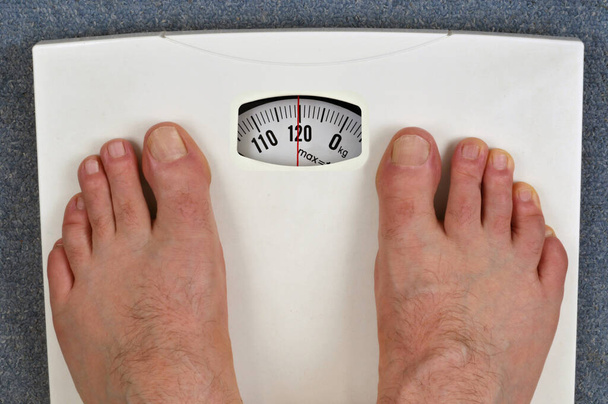 Πόδια ενός άντρα σε μια ζυγαριά μπάνιου βάρους 120 κιλών  - Φωτογραφία, εικόνα