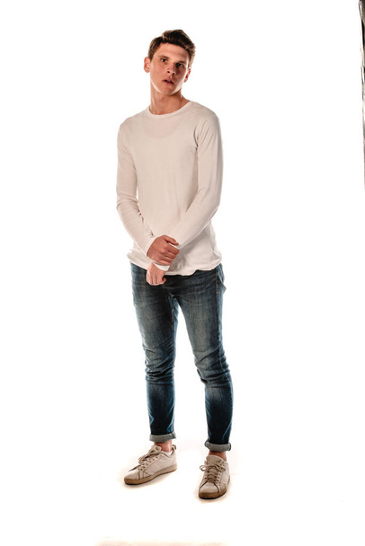 Porträt eines trendigen Typen mit weißem Langarmshirt und blauer Jeanshose - Foto, Bild