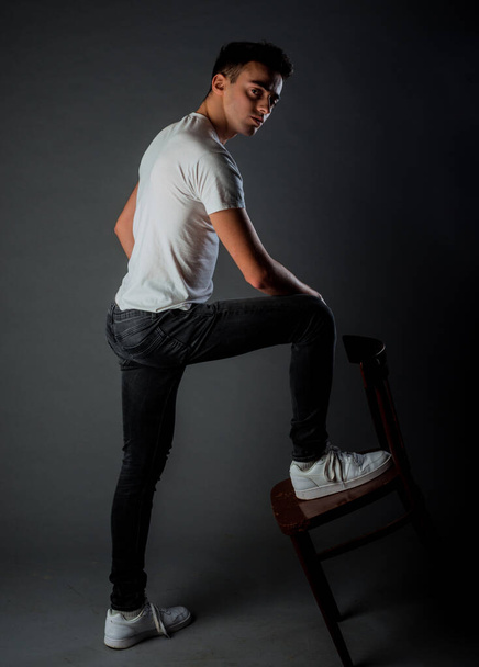 Trendy schöner Mann posiert in trendigem weißen T-Shirt und schwarzer Jeanshose - Foto, Bild