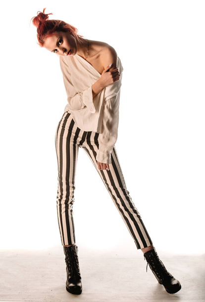 Tyylikäs muoti punapää tyttö poseeraa trendikkäitä vaatteita vastaan valkoinen tausta - Valokuva, kuva