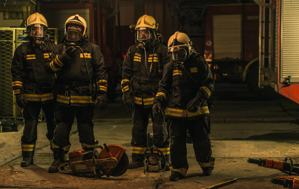 Ομάδα πυροσβεστών με στολή που ποζάρουν μέσα στο γκαράζ της πυροσβεστικής - Φωτογραφία, εικόνα