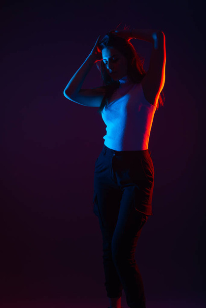 Блакитний і червоний світловий портрет жіночої моделі на чорному тлі з високим контрастом
 - Фото, зображення
