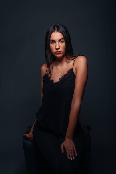 Vášnivý portrét atraktivní brunetky hledící do kamery a pózující na tmavém pozadí ve studiu - Fotografie, Obrázek