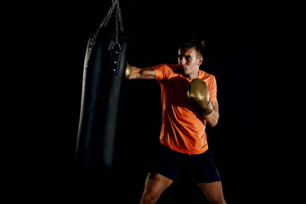 Professionele gespierde kick bokser training op een bokszak tijdens de voorbereiding op het volgende gevecht - Foto, afbeelding