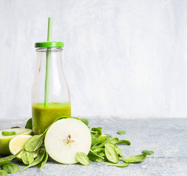 Fresh green smoothie in bottle  with apple and spinach on light background, front view.  Healthy, diet or detox beverage concept - Photo, image
