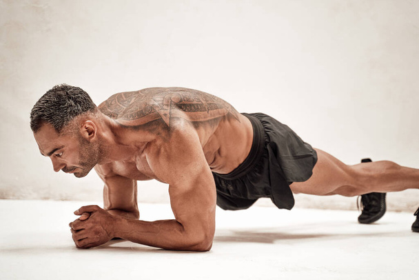 Hombre sano y enérgico haciendo ejercicios de tablón, centrado y buscando fuerte
 - Foto, Imagen