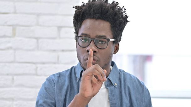 Fiatal afrikai férfi tesz ujj a száját - Fotó, kép