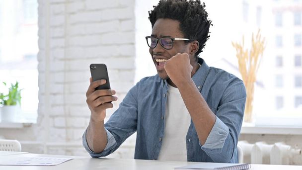 Mladý africký muž jásající Vyhrajte na chytrém telefonu - Fotografie, Obrázek