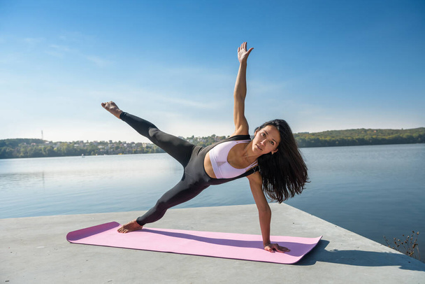 Jonge brunette vrouw oefenen yoga vroege ochtend voor werktijd. Concept van welzijn en gezonde levensstijl - Foto, afbeelding