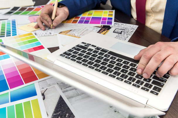 Architekt wybierając kolory do dekoracji wnętrz pokoju z laptopem i próbki kolorów. Projektant wnętrz pracuje z paletą kolorów i szkicem domu - Zdjęcie, obraz