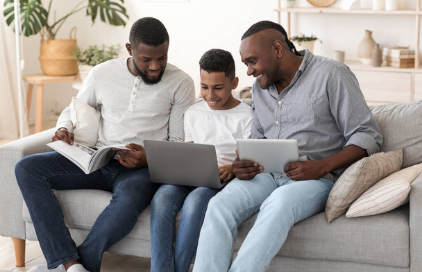 Африканська чоловіча сім'я з ноутбуком, цифровий планшет і журнал вдома
 - Фото, зображення