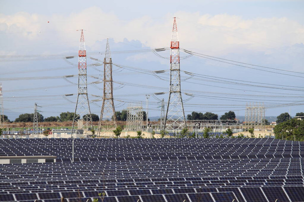 背景に電力線塔のある再生可能エネルギーを利用した発電所 - 写真・画像