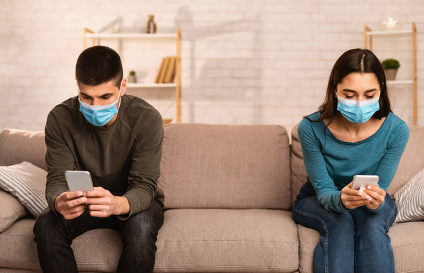 Couple portant un masque chirurgical à l'aide de téléphones cellulaires
 - Photo, image