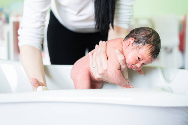 Mother bathes her baby for the first time in baby room. Unrecognizable mother bathing her newborn baby - Fotoğraf, Görsel