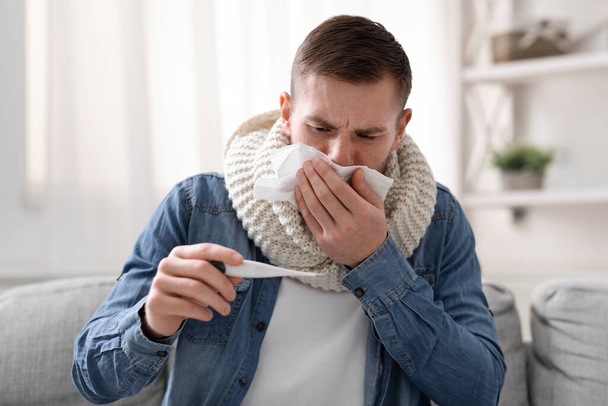 Coughing guy checking his high body temperature at home - Photo, Image