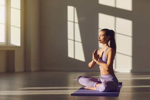 Menina ioga mulher na posição de lótus relaxa pela manhã ao nascer do sol no quarto
. . - Foto, Imagem