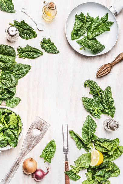 緑の有機ほうれん草の葉、成分と白い木製の背景にキッチンツールで調理準備のトップビュー。ビーガンまたはベジタリアンの栄養,食事,デトックスと健康食品の概念 - 写真・画像