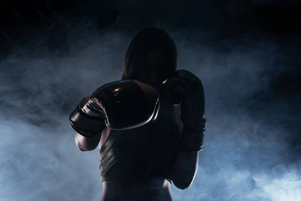 Silhouette portrait with white smoke in the background of a female model with boxing gloves - Foto, Imagen