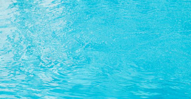 Hintergrund der Wasseroberfläche. Blaues Poolwasser mit Sonnenreflexen. Wellen von Wasser im Pool. - Foto, Bild