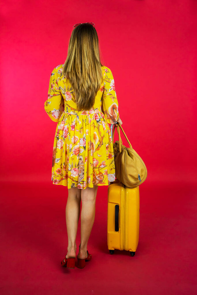Rear view of young woman with bags for vacation walking in the studio - Foto, Imagen