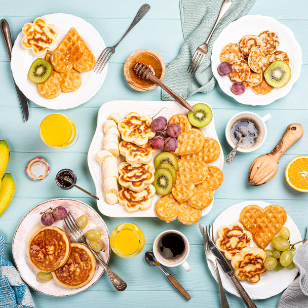 Healthy breakfast with fresh hot waffles hearts, pancakes flowers - Фото, изображение