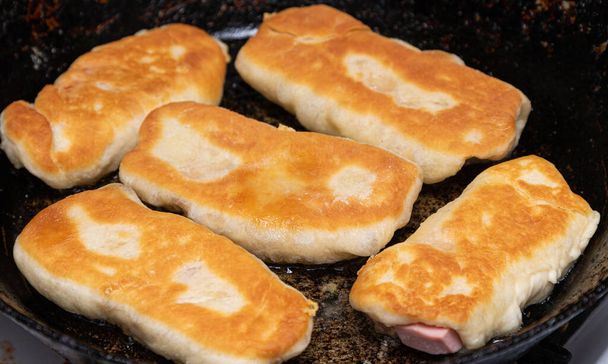 Fried pies with sausage and cheese in a pan. - Photo, Image