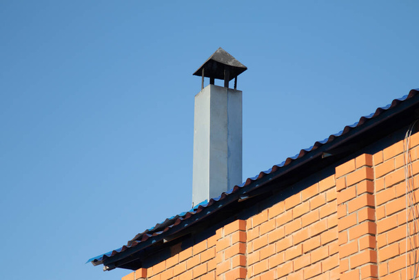 Metal pipe on the roof of the house against the sky. - Photo, Image