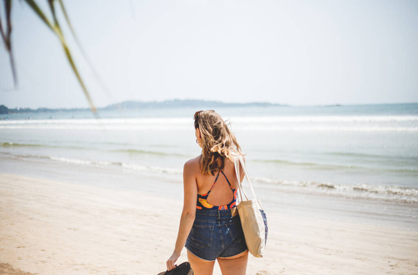 Beautiful woman in bikini walking on the beach of the ocean. Travel vacation, freedom and relaxation. - Фото, изображение
