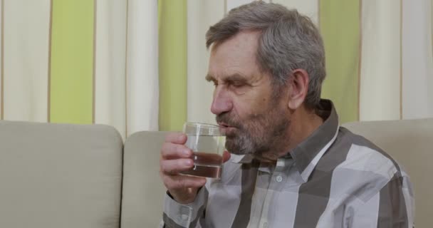 Elderly man drinking a glass of water. - Кадры, видео