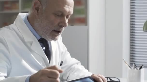 Doctor showing a radiograph to a patient using a tablet - Záběry, video