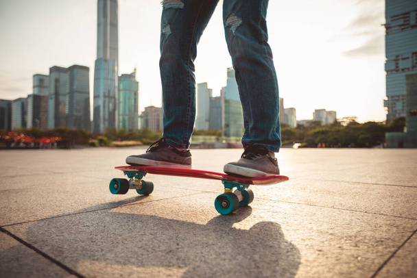 Skateboarder skateboarding over sunset in urban city with skyscrapers - Foto, Imagen
