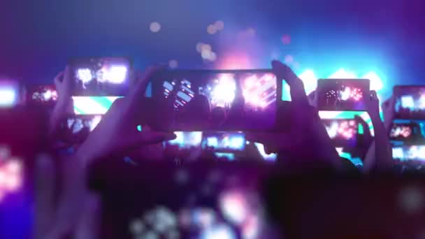 ファンはスマートフォンでビデオを録画しています。多くのスマートフォン。音楽の概念。ライブストリーム。話だ。群衆はコンサートを見て、歌い、飛び跳ねる。舞台照明を撫でる。コンサートの幸せな人たち. - 映像、動画