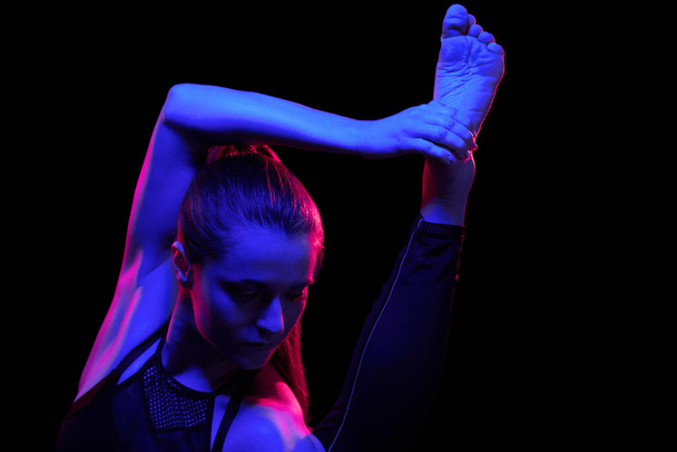 Giovane donna in forma che pratica yoga. Luce al neon. Moderna rappresentazione fantascientifica dello yoga. Copia spazio
 - Foto, immagini