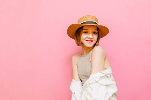 Pěkně usměvavá turistka izolovaná na pastelově růžovém pozadí, dívá se do kamery a usmívá se. Dáma v klobouku a letní oblečení stojí na růžovém pozadí. Kopírovat prostor - Fotografie, Obrázek